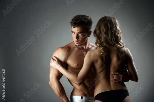 Studio photo of bodybuilder hugs topless model