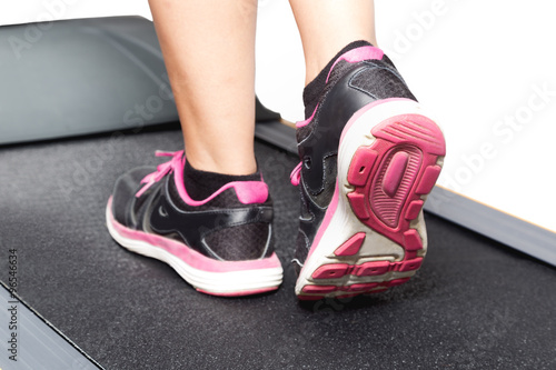 Girl exercise on treadmill on pink black sport shoes with white space