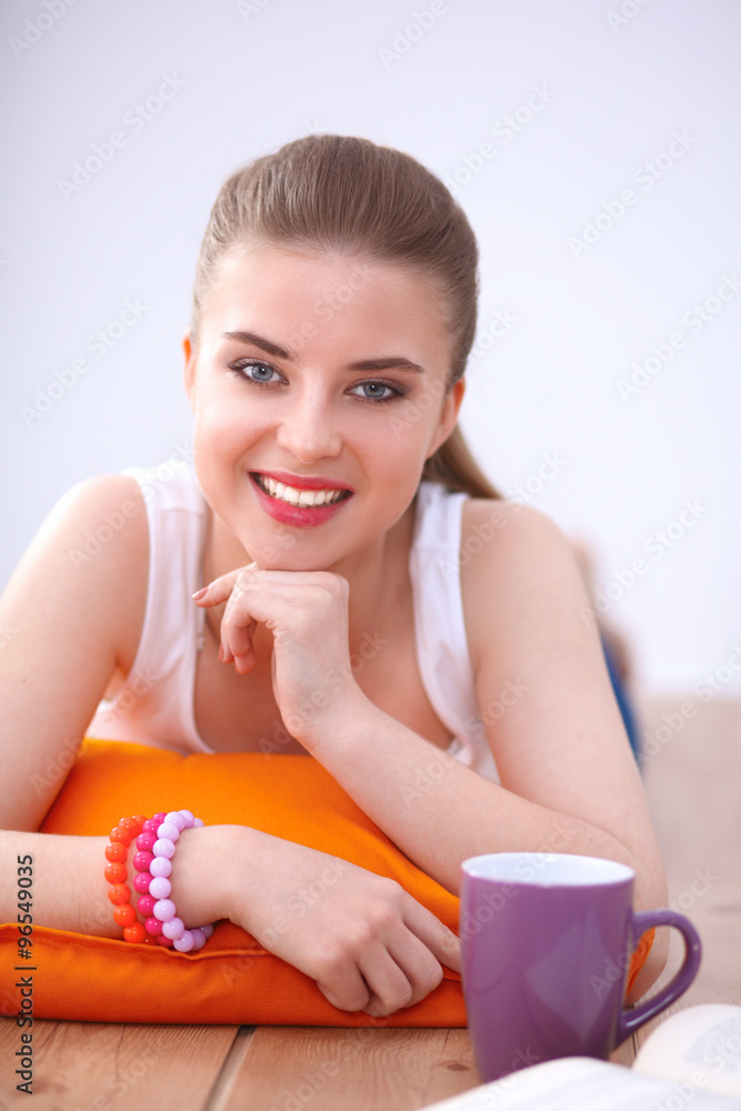 Smiling young woman lying on a white floor with pillow Smiling young woman lying on a white floor with pillow