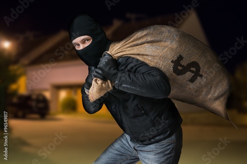 Photo Robber is running away and carying full bag of money at night.