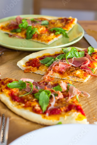 Slices of italian style pizza with arugula and prosciutto