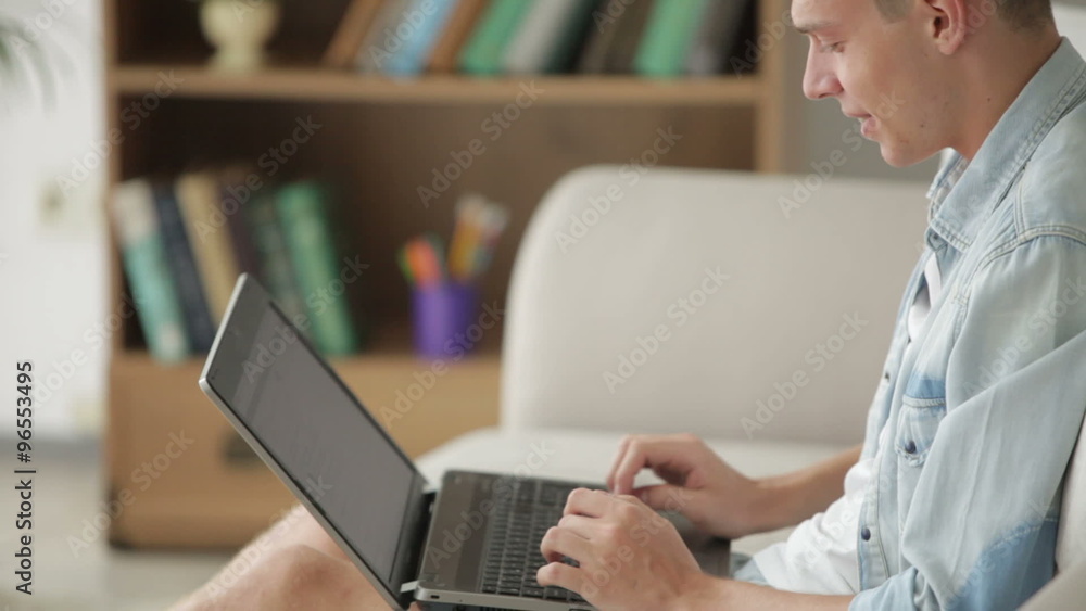 Handsome man sitting on couch and using laptop Handsome man sitting on couch and using laptop