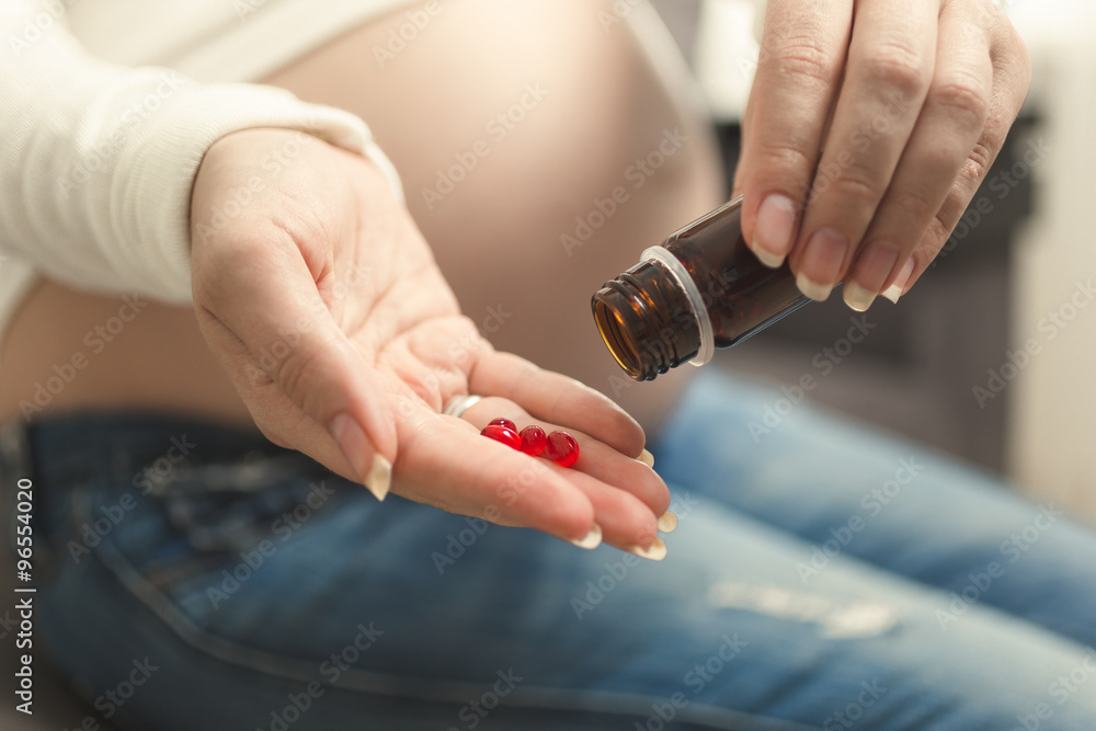 Pregnant woman emptying bottle with medicines Pregnant woman emptying bottle with medicines