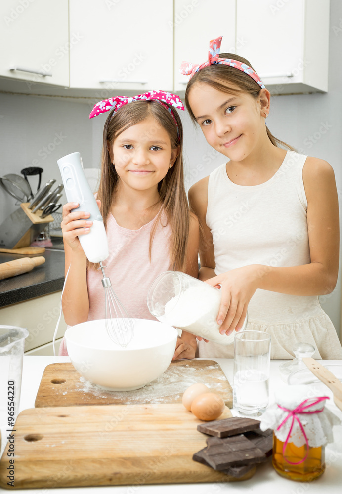 two sister mixing ingredients for dough in big bowl on kitchen two sister mixing ingredients for dough in big bowl on kitchen