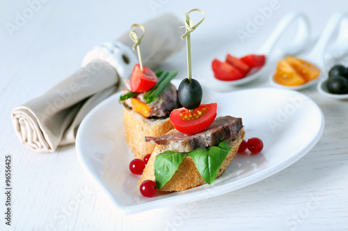 Tasty canapes on wooden table, close up