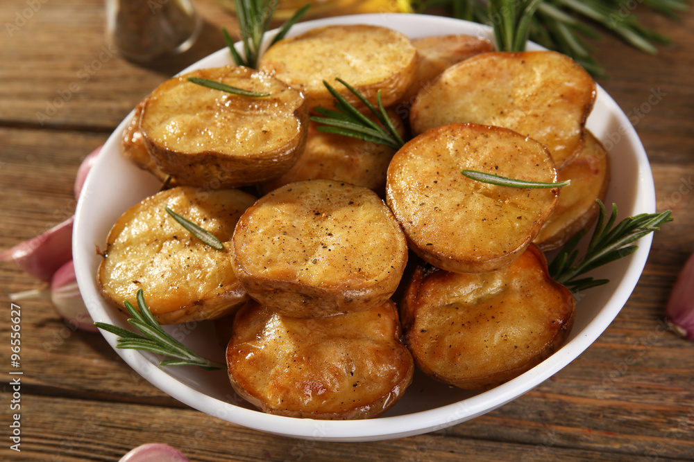 Delicious baked potato with rosemary in bowl on table close up Delicious baked potato with rosemary in bowl on table close up