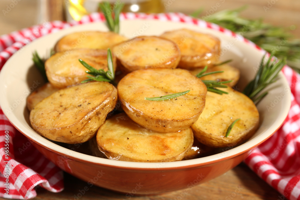 Delicious baked potato with rosemary in bowl on table close up Delicious baked potato with rosemary in bowl on table close up