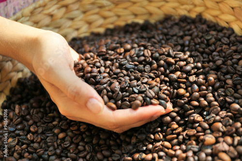 Basket with coffee beans and females hand  close up