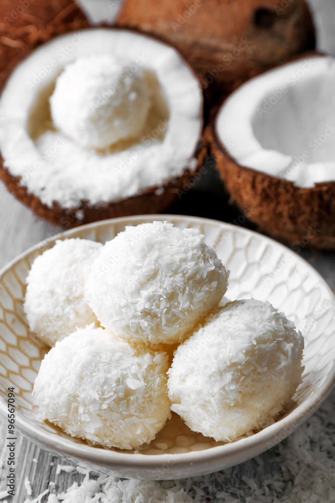 Candies in coconut flakes and fresh coconut on color wooden background Candies in coconut flakes and fresh coconut on color wooden background