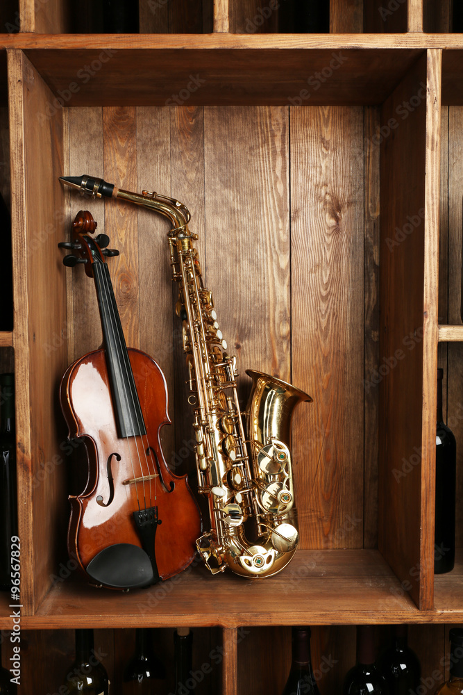 Naklejka premium Musical instruments: saxophone, violin on wooden background