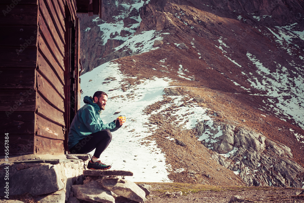Man outside a mountain home drinking coffee