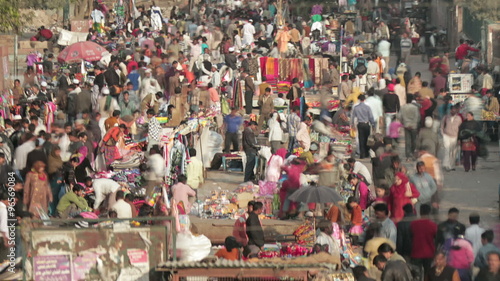Time-lapse of crowds in street market in Delhi, India. Camera pans right to left