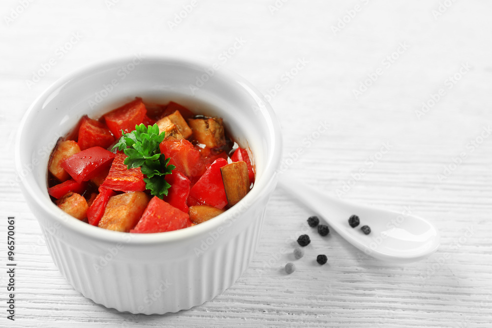 Tasty vegetarian ratatouille made of eggplants, squash, tomatoes in bowl on wooden table background Tasty vegetarian ratatouille made of eggplants, squash, tomatoes in bowl on wooden table background