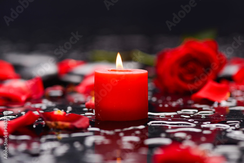 Beautiful red rose petals with candle and therapy stones 