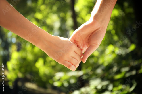Young couple holding hands on nature background © Africa Studio