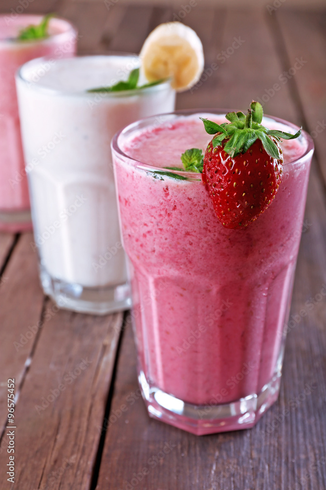 Glasses of fresh cold smoothie with fruit and berries, on wooden background Glasses of fresh cold smoothie with fruit and berries, on wooden background