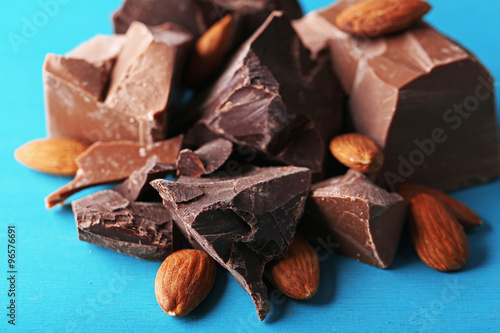 Black chocolate pieces with nuts on color wooden background