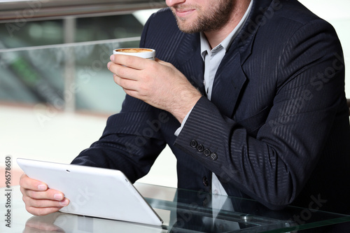 Young attractive businessman having lunch and working in a cafe, close-up