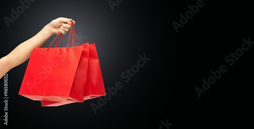 close up of hand holding red shopping bags