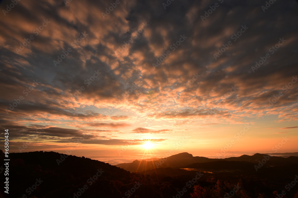Beautiful sunset at the mountains. Colorful landscape with sun and orange sky
