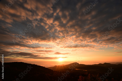 Beautiful sunset at the mountains. Colorful landscape with sun and orange sky  