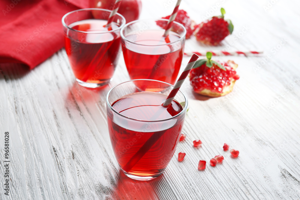 Three glasses of tasty juice and garnet fruit, on wooden background Three glasses of tasty juice and garnet fruit, on wooden background