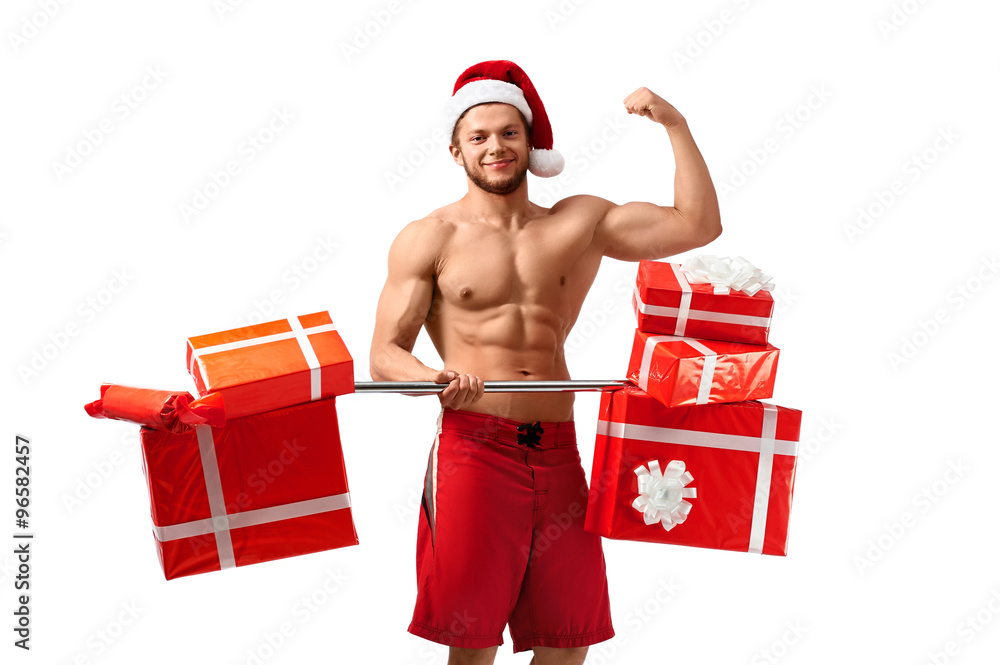 Christmas power. Muscular Santa Claus showing off his biceps holding a barbell full of presents Christmas power. Muscular Santa Claus showing off his biceps holding a barbell full of presents