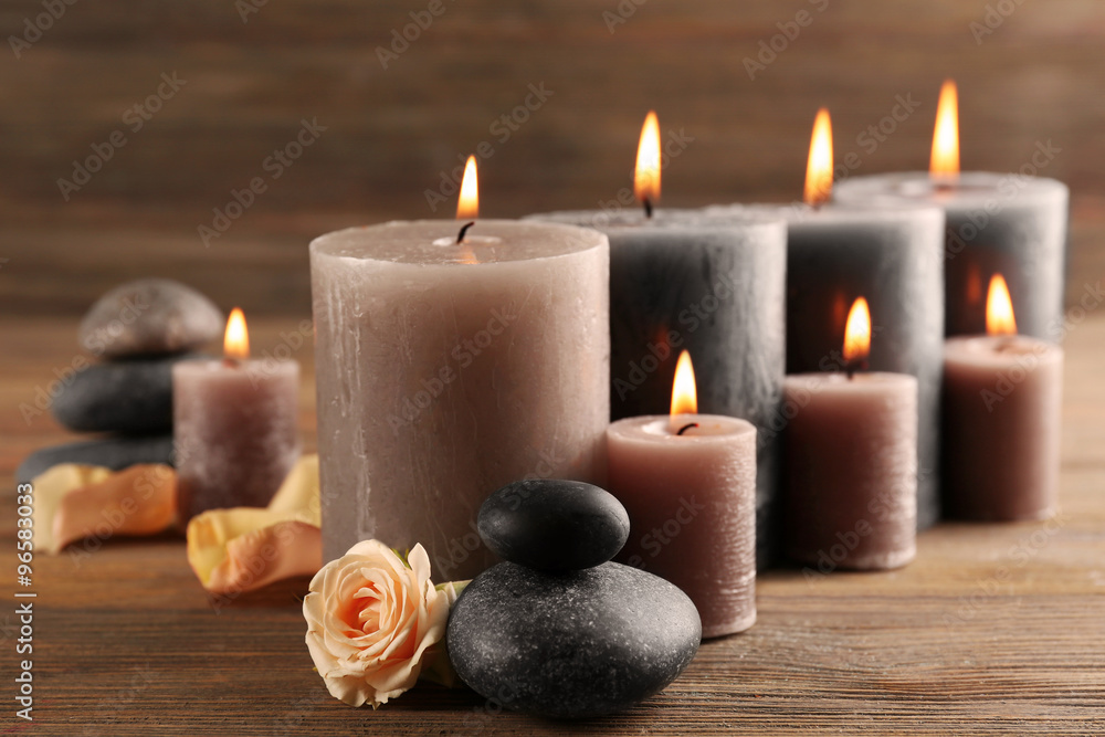 Alight wax grey candles with roses on wooden background Alight wax grey candles with roses on wooden background