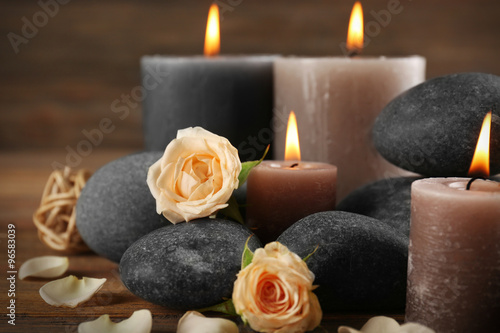 Beautiful relax composition of alight candles  pebbles and flowers on wooden background