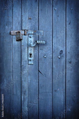 Old vintage door handle with a rusty padlock on a stunning blue colored wood door © steevy84