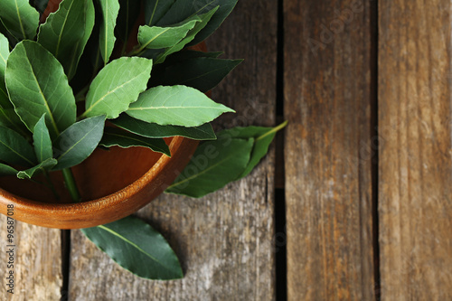 Fresh bay leaves in bowl on vintage wooden table