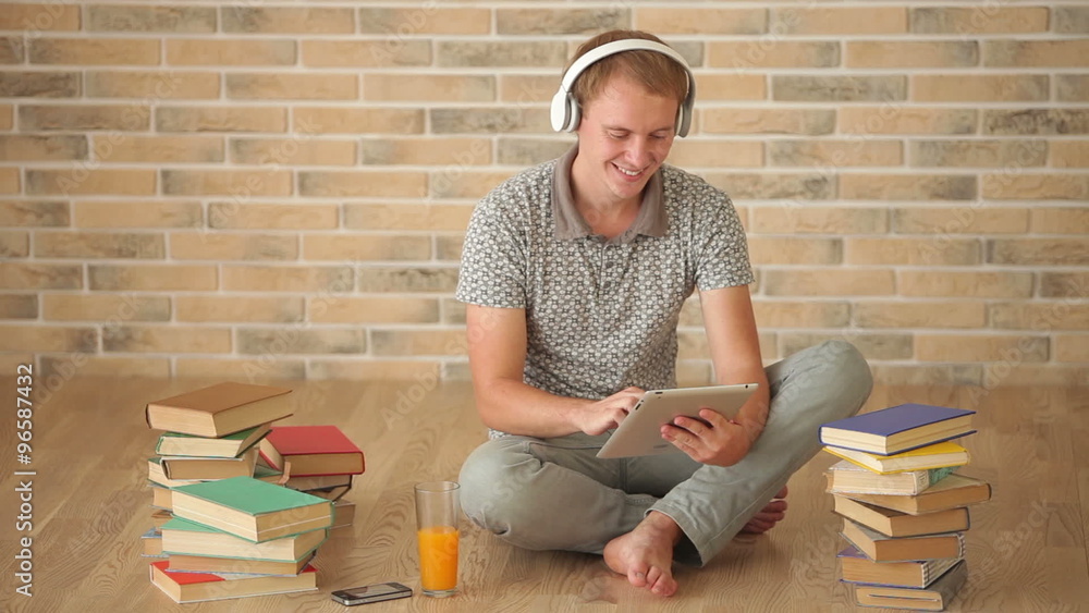 Handsome guy sitting on floor using touchpad looking at camera and smiling Handsome guy sitting on floor using touchpad looking at camera and smiling