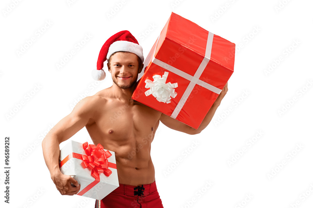 Ready to celebrate. Sexy attractive guy wearing Santa Claus hat smiling holding presents showing off his ripped body Ready to celebrate. Sexy attractive guy wearing Santa Claus hat smiling holding presents showing off his ripped body