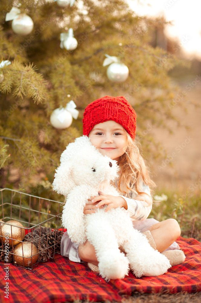 Smiling kid girl holding white teddy bear with christmas decorations outdoors. Childhood. Looking at camera. Smiling kid girl holding white teddy bear with christmas decorations outdoors. Childhood. Looking at camera.