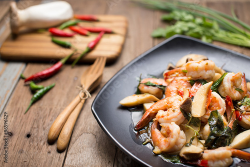 Stir Fried shrimp with Holy Basil with raw material on the wooden background