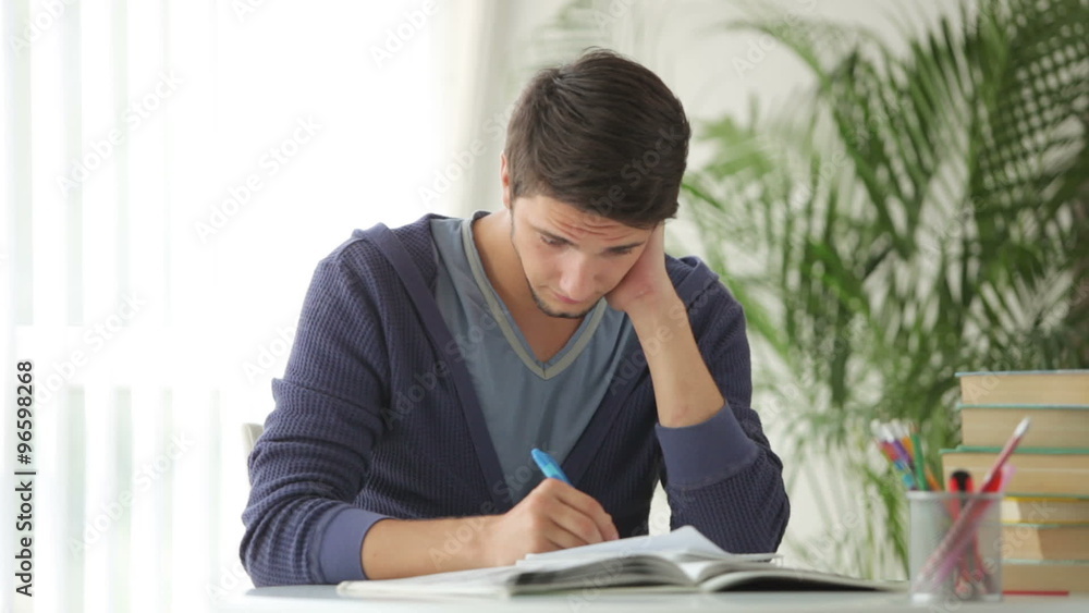 Young man sitting at table and studying with books Young man sitting at table and studying with books