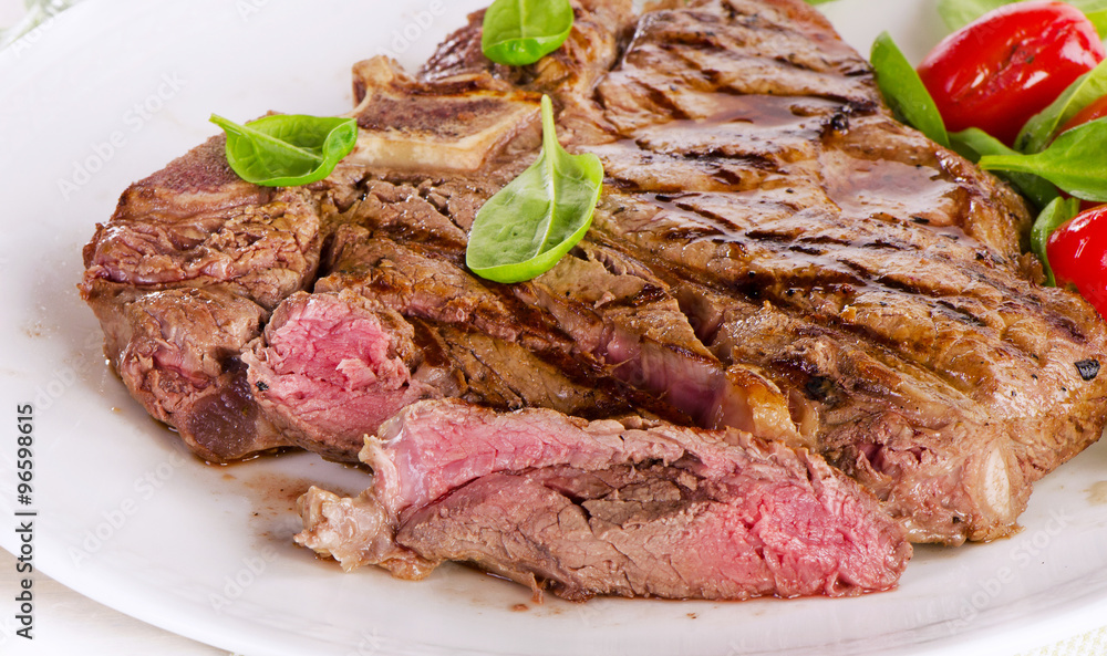 Beef steak served with  green salad.