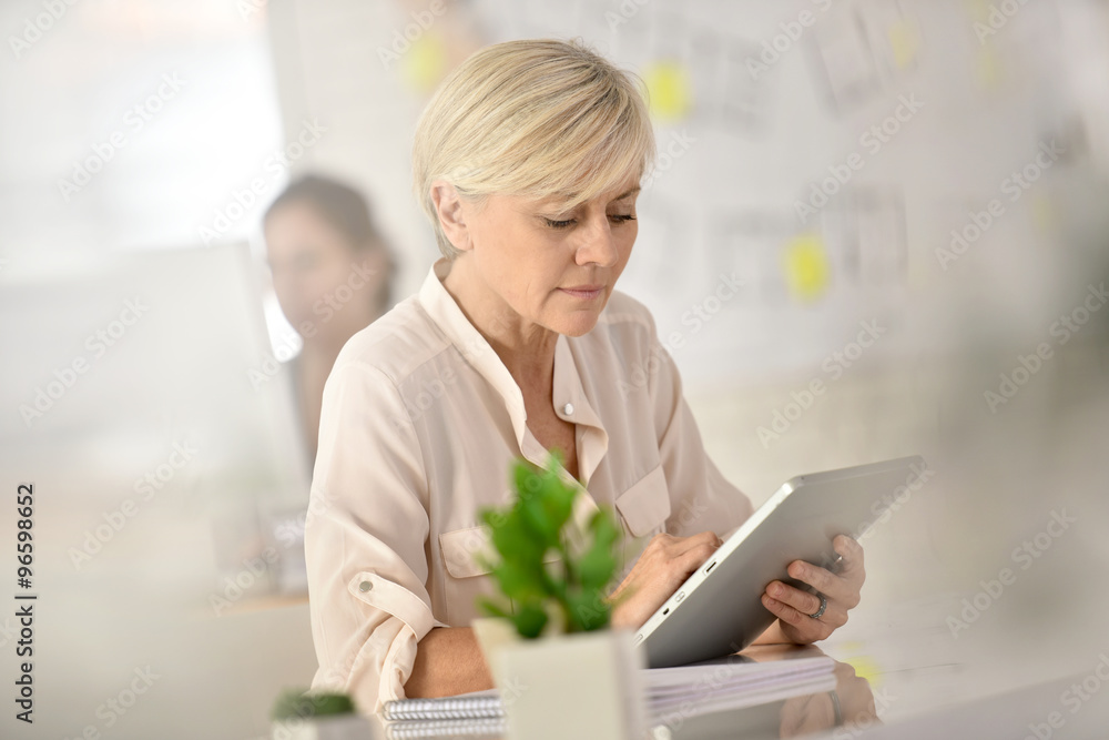 Senior businesswoman in office working on digital tablet Senior businesswoman in office working on digital tablet