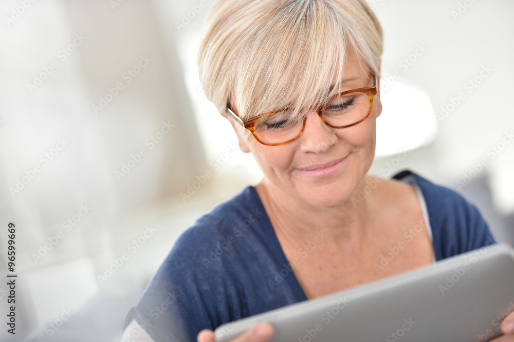Senior woman with eyeglasses browsing on digital tablet Senior woman with eyeglasses browsing on digital tablet