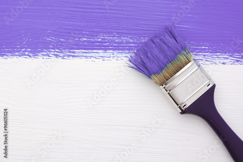 Stripe of purple paint with a paintbrush on white