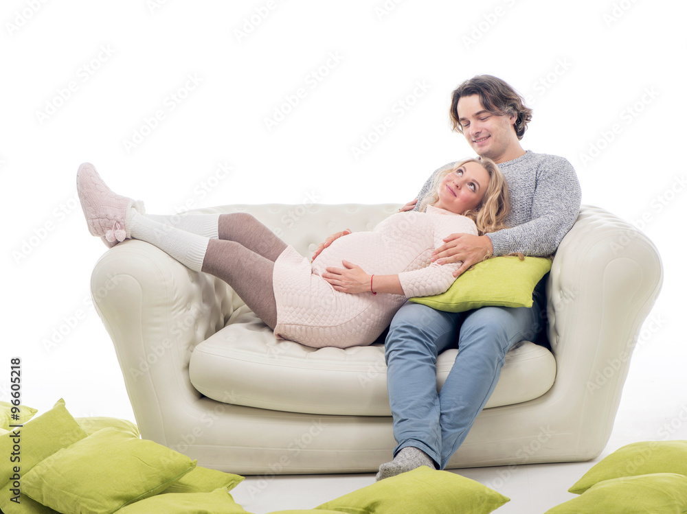 Pregnant fasion woman in knitted sweater with husband sitting on the sofa Pregnant fasion woman in knitted sweater with husband sitting on the sofa