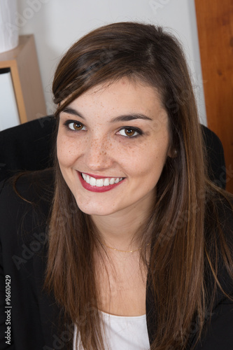 Portrait of young smiling woman sitting in her desk at office Close up.