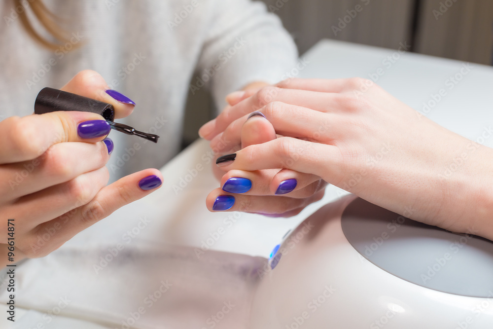 Beautician paints nails woman client in the salon Beautician paints nails woman client in the salon