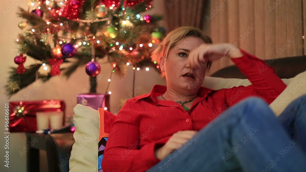Depressive woman lying on a sofa in living room with christmas decorating Depressive woman lying on a sofa in living room with christmas decorating