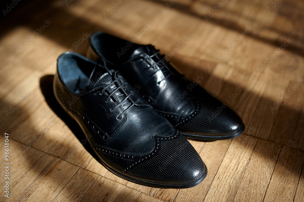 pair of men's black leather ankle shoes placed on wooden floor pair of men's black leather ankle shoes placed on wooden floor