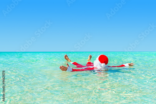 Santa Claus swimming in ocean water, Christmas concept
