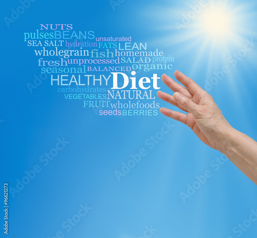 Reaching for a better diet - female hand reaching upwards to a diet word cloud on a blue sky background with a bright sun burst and plenty of  copy space below