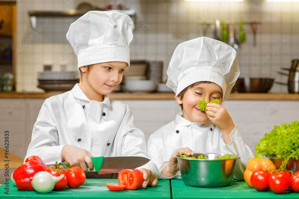 Funny happy chef boys cooking at restaurant kitchen. concept of vegetarianism Funny happy chef boys cooking at restaurant kitchen. concept of vegetarianism