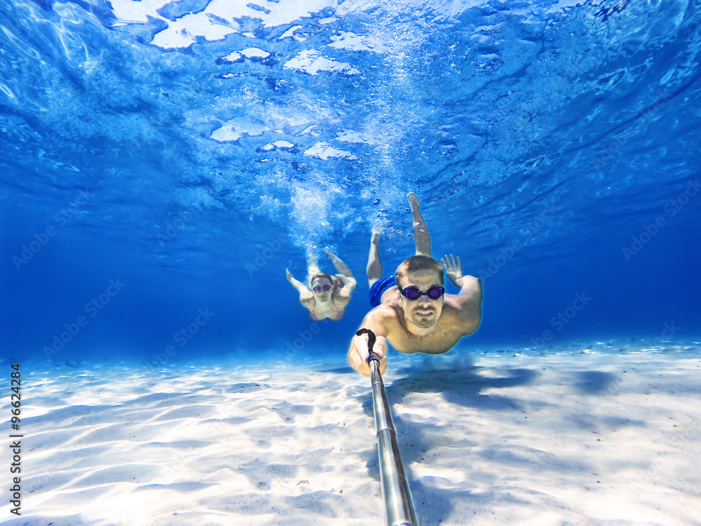 Underwater selfie shot with selfie stick. Couple swimming at the bottom of  the sea. Deep blue sea. Wide angle shot. Stock Photo | Adobe Stock