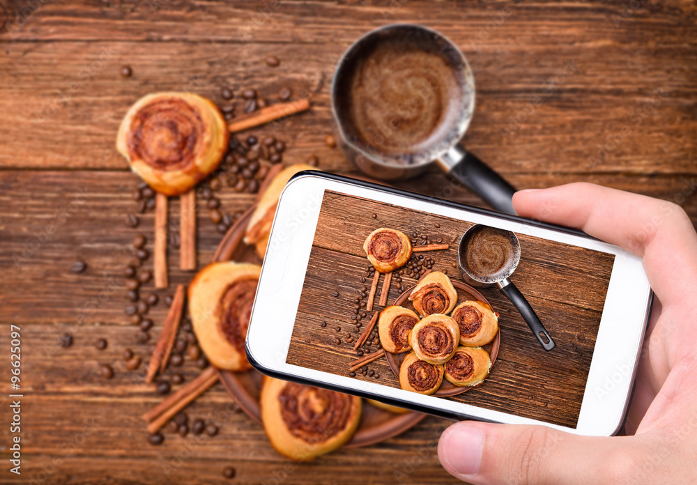 Hands taking photo cinnamon rolls with smartphone. Hands taking photo cinnamon rolls with smartphone.